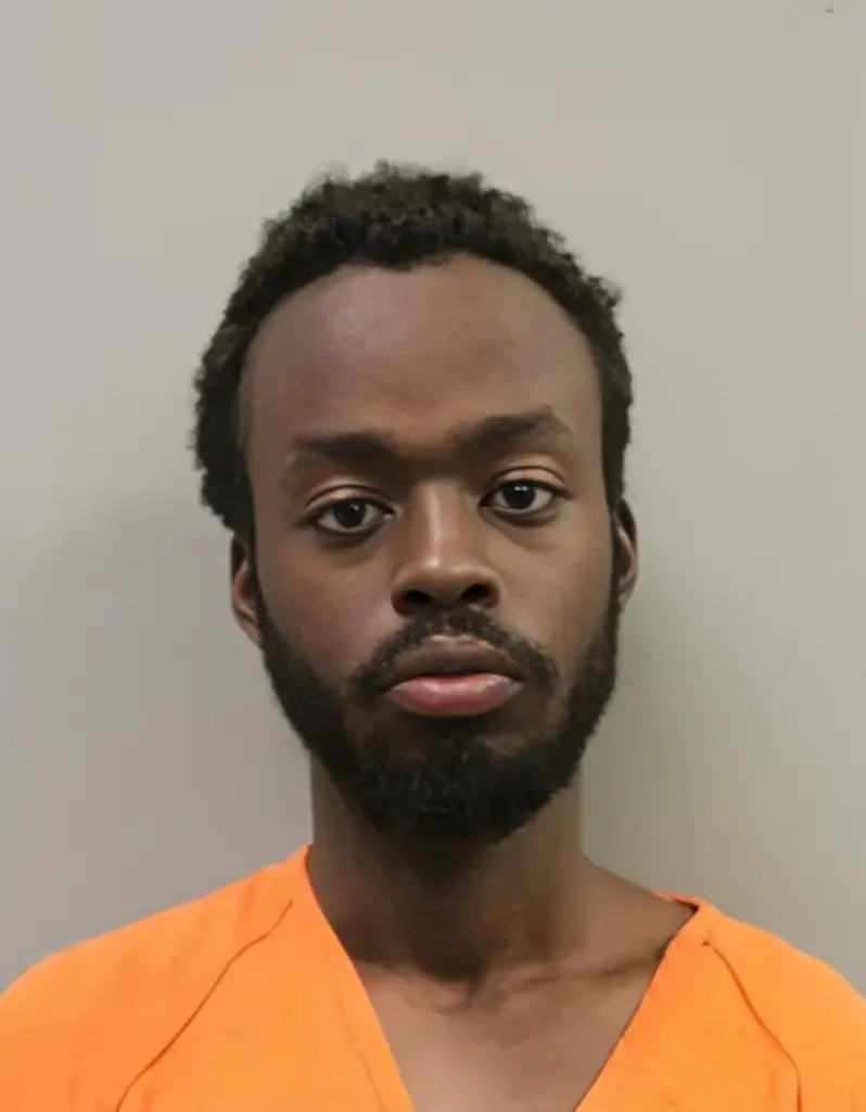 Emmanuel Mbwavi, a Black man with a beard, wearing an orange shirt.