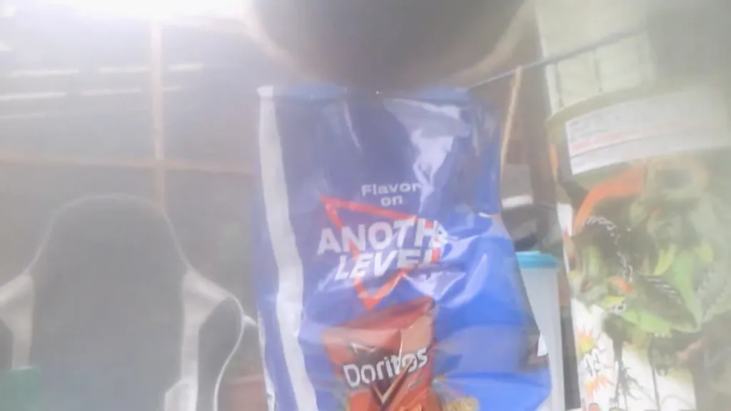 Blue Doritos bag with "Flavor on ANOTHER LEVEL" next to a gaming chair and a decorative container.