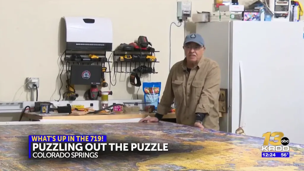 A man standing over a large completed jigsaw puzzle, with text overlay: 
