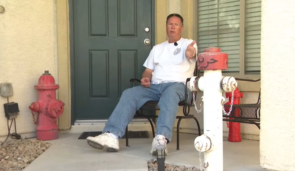 Brent Saba points at a fire hydrant brought home from his deployment in Iraq and put on display in his front yard.