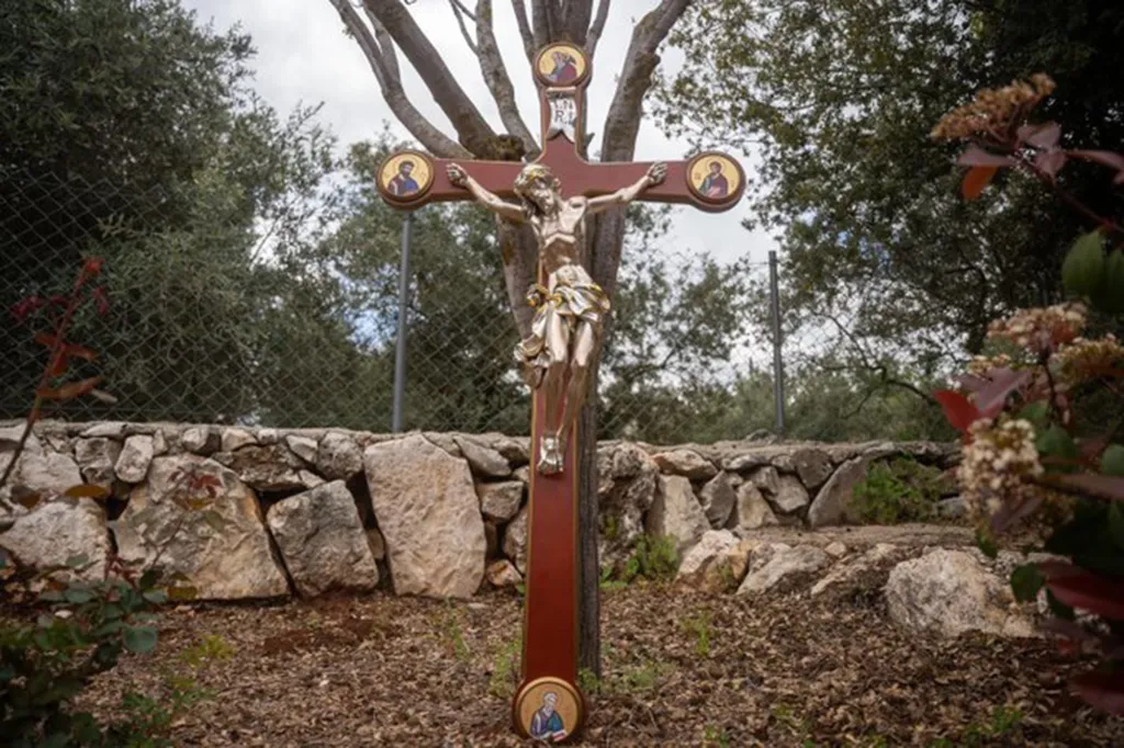 A newly replaced crucifix featuring Jesus on the cross, surrounded by iconography, stands in Debel, Lebanon.