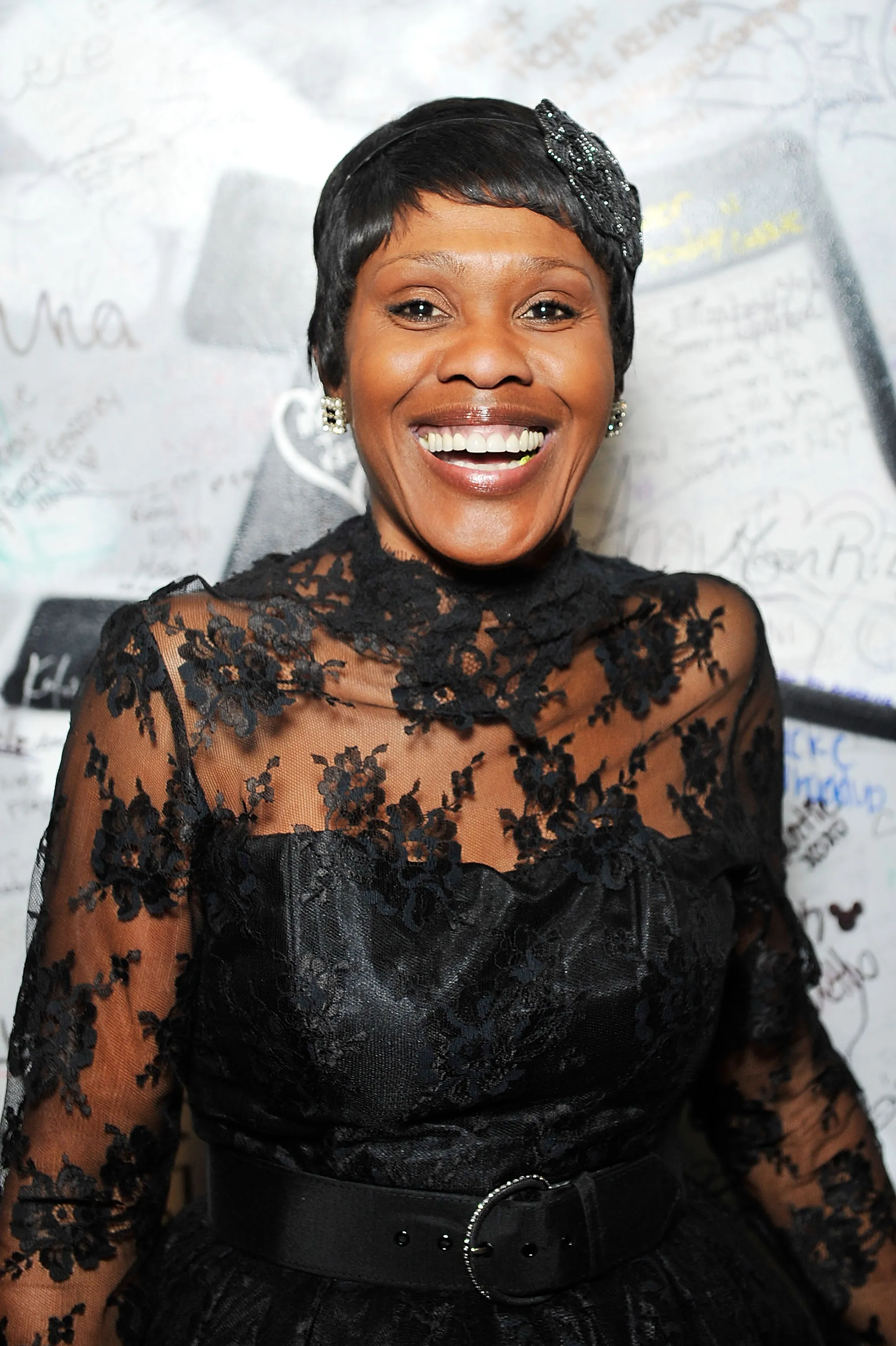 Actress Dee Freeman smiles wearing a black lace dress and a sparkly headband.