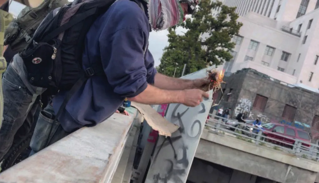 Adam Palermo lights an object on fire while on an overcrossing.