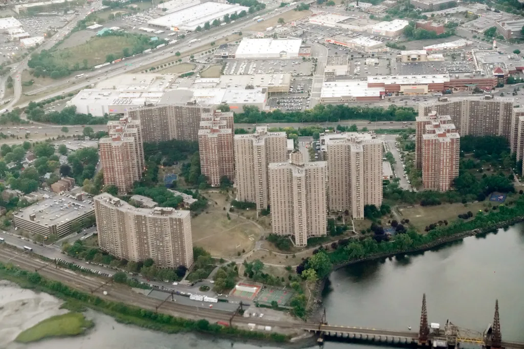 Aerial view of Co-Op City in the Bronx, NY, showing residential buildings, a highway, and a body of water.