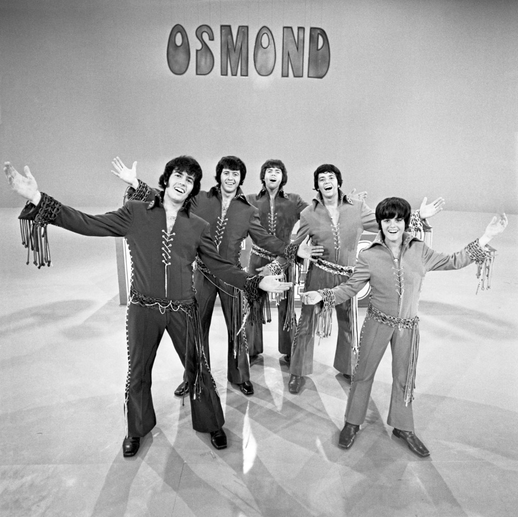 The Osmond Brothers (Alan, Wayne, Merrill, Jay, and Donny) posing on a stage during their 1971 TV special.