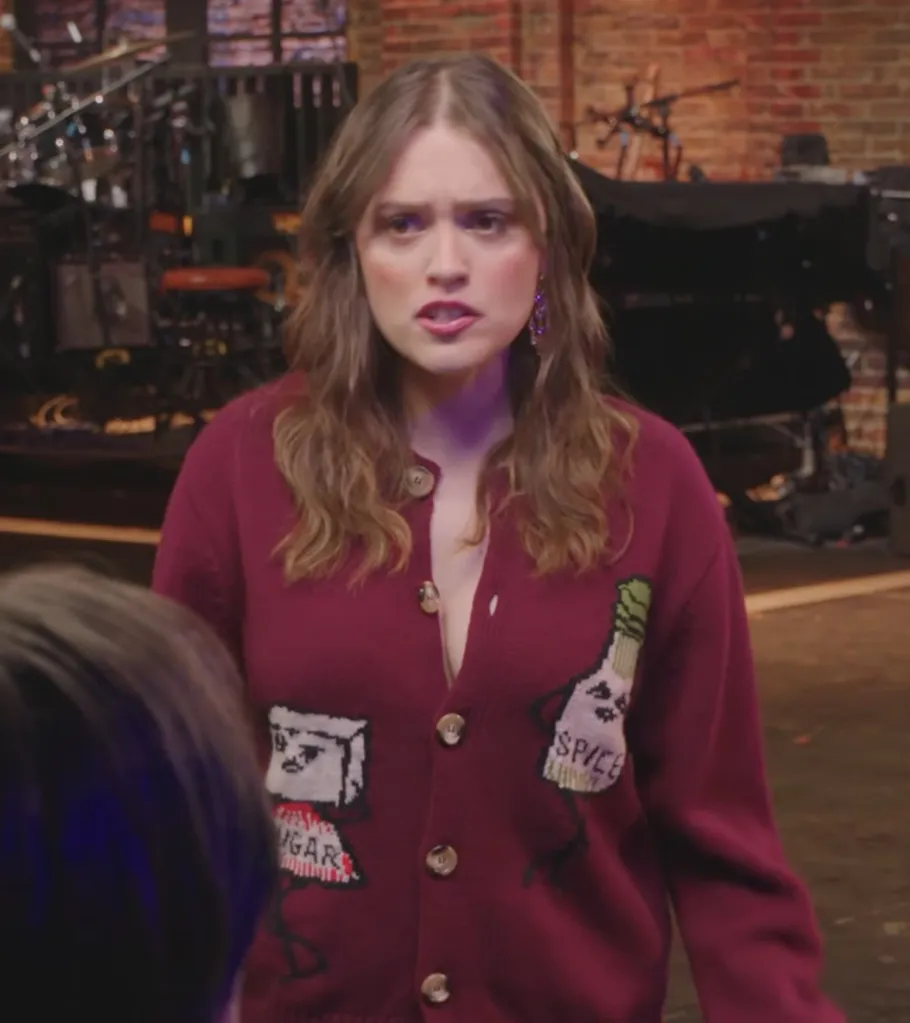 Aimee Lou Wood wearing a maroon cardigan with "sugar" and "spice" embroidered patches.