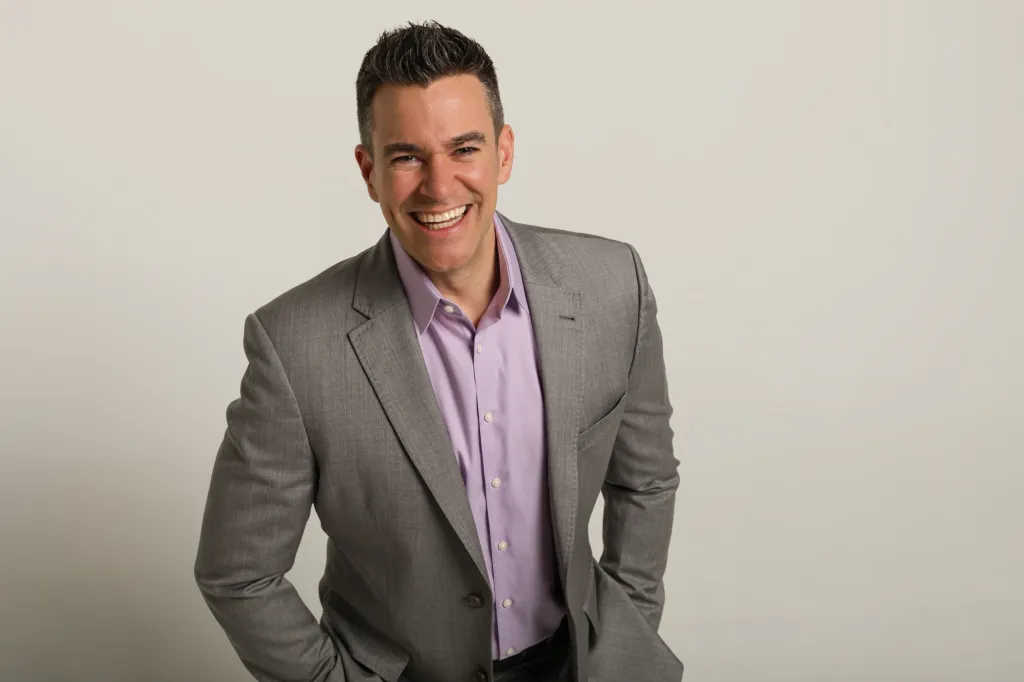 Headshot of Jeff Civillico, a man in a grey suit and lavender shirt, smiling.