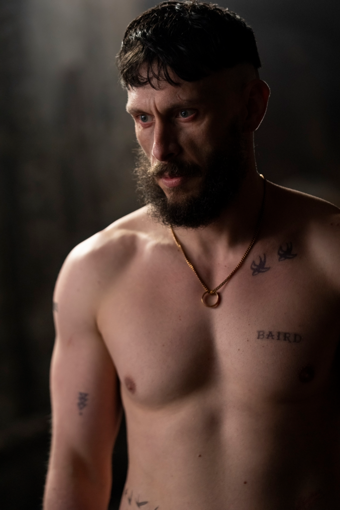 Richard Gadd shirtless with tattoos, wearing a gold necklace.