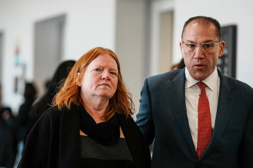 Asa Ellerup, wife of Rex Heuermann, and her attorney, Robert Macedonio, walk towards a courtroom.