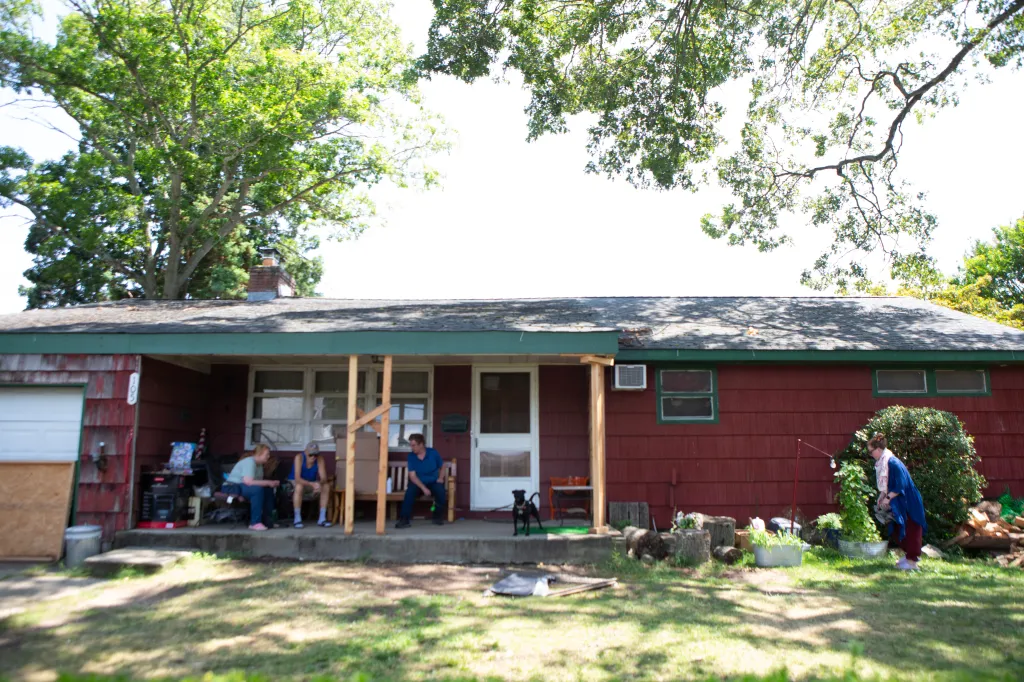 Family members sitting on the porch of a red house.
