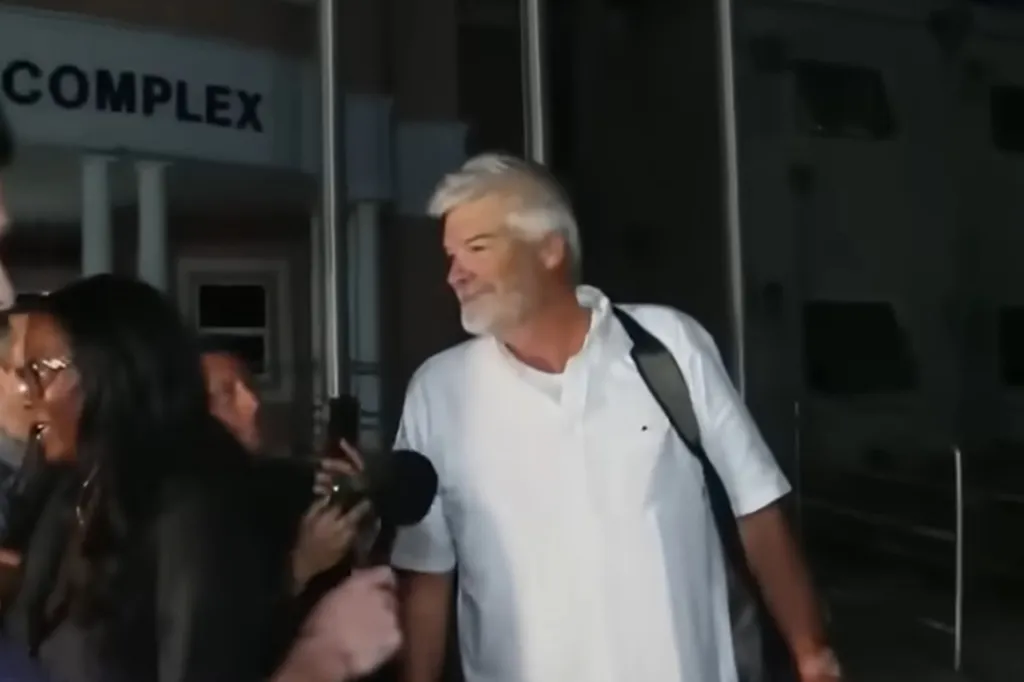 Brian Hooker, wearing a white shirt, being interviewed by reporters after his release.