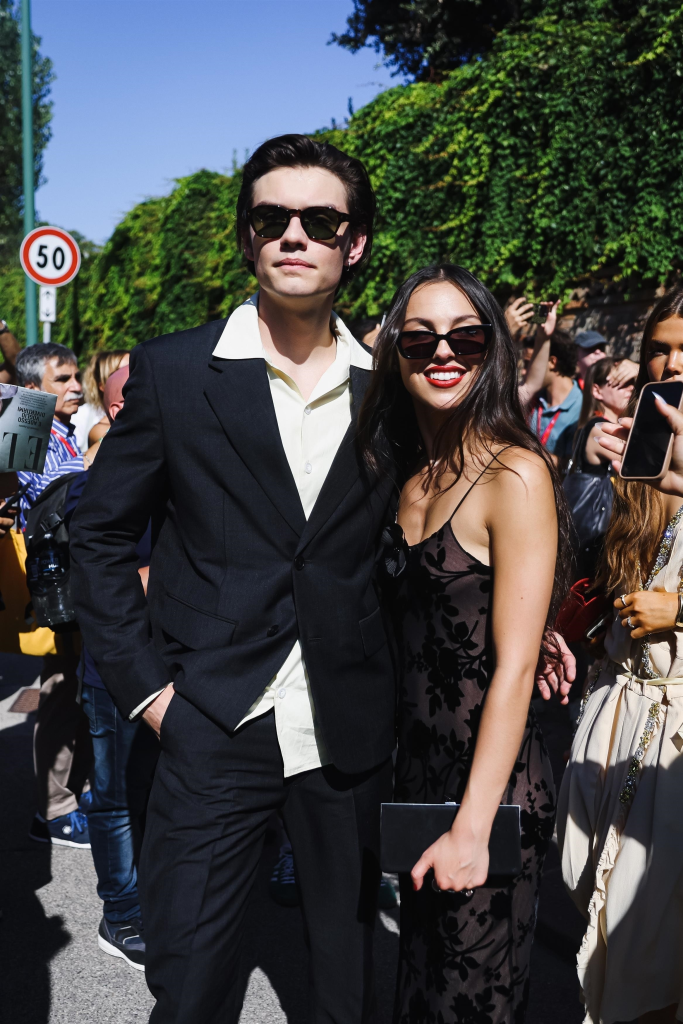 Louis Partridge in a suit and Olivia Rodrigo in a black dress attending the 81st Venice International Film Festival.