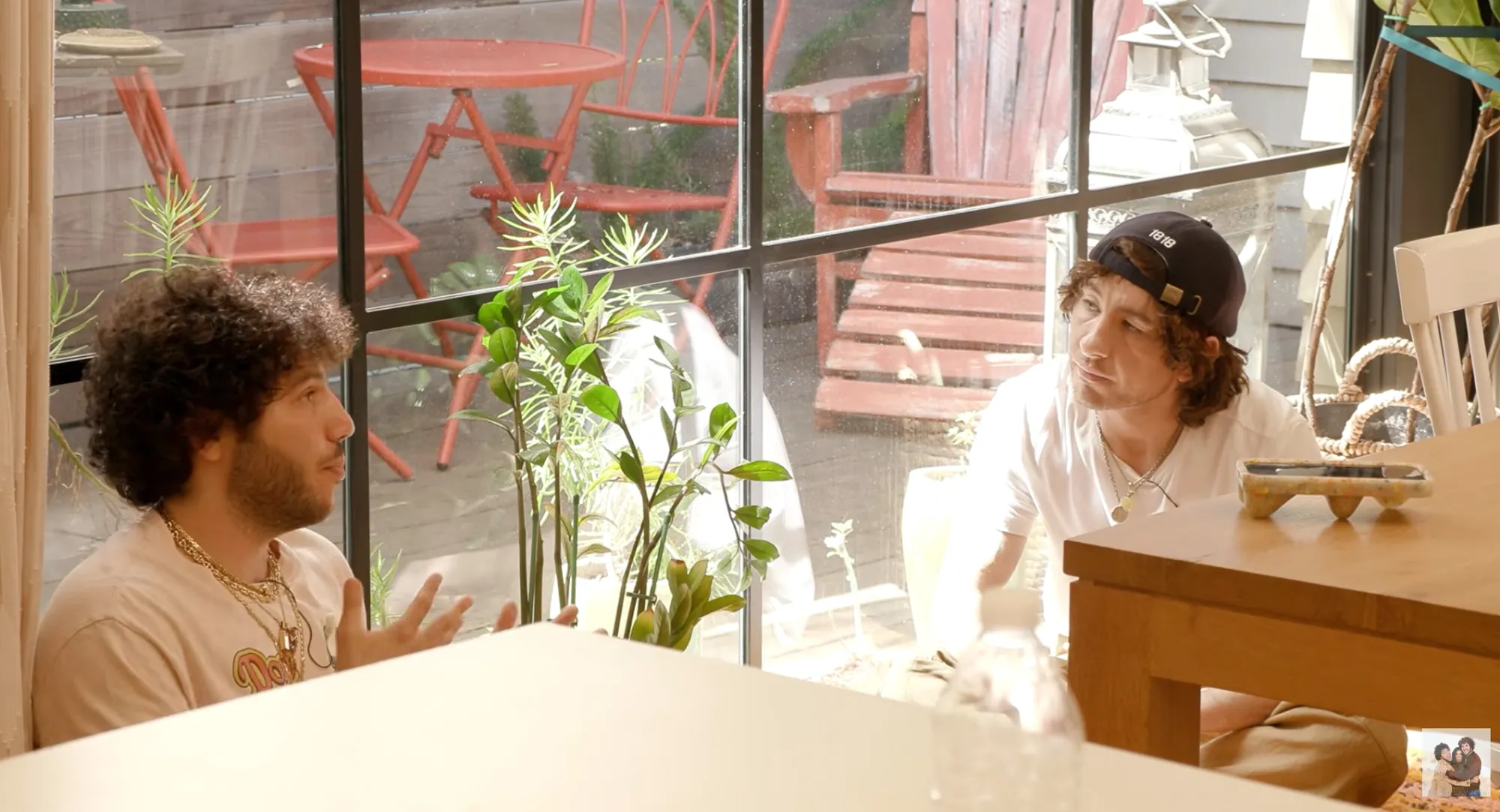 Two men conversing in a sunlit room.