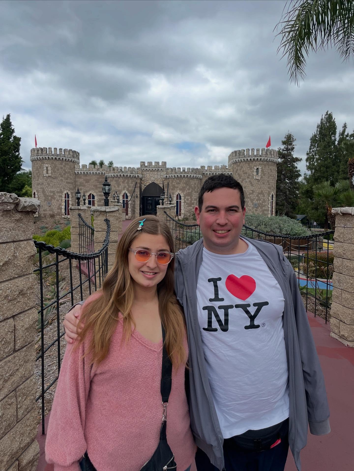 Abbey Romeo and David Isaacman smiling in front of a stone castle.