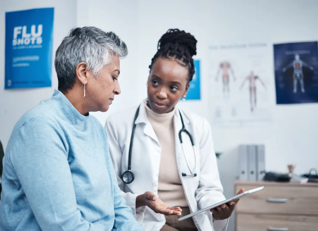 A doctor discusses health planning with a senior patient using a tablet.