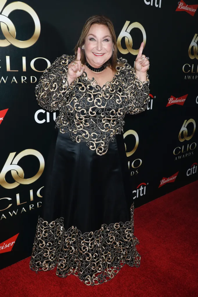 Wendy Kaufman in a black and gold embroidered dress, pointing upwards at the 60th Clio Awards.