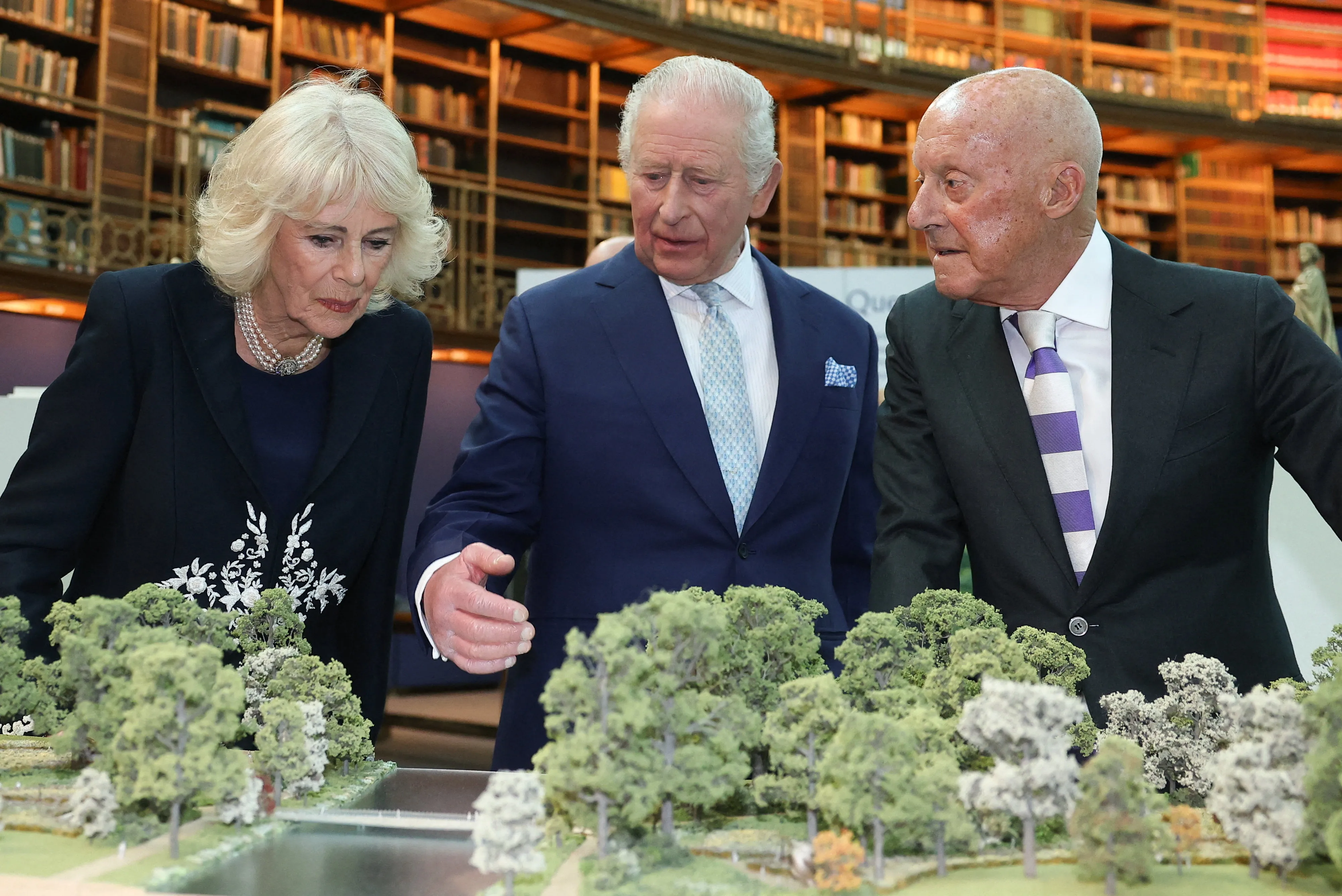 King Charles III and Queen Camilla looking at a miniature landscape model with architect Norman Foster.