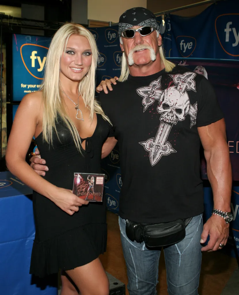 Brooke Hogan holding her album "Undiscovered" with Hulk Hogan at an FYE signing event.