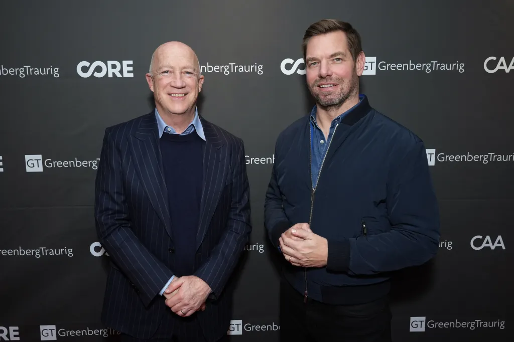 Bryan Lourd and Eric Swalwell smiling, standing in front of a black backdrop with white logos for "Greenberg Traurig", "CORE", and "CAA".