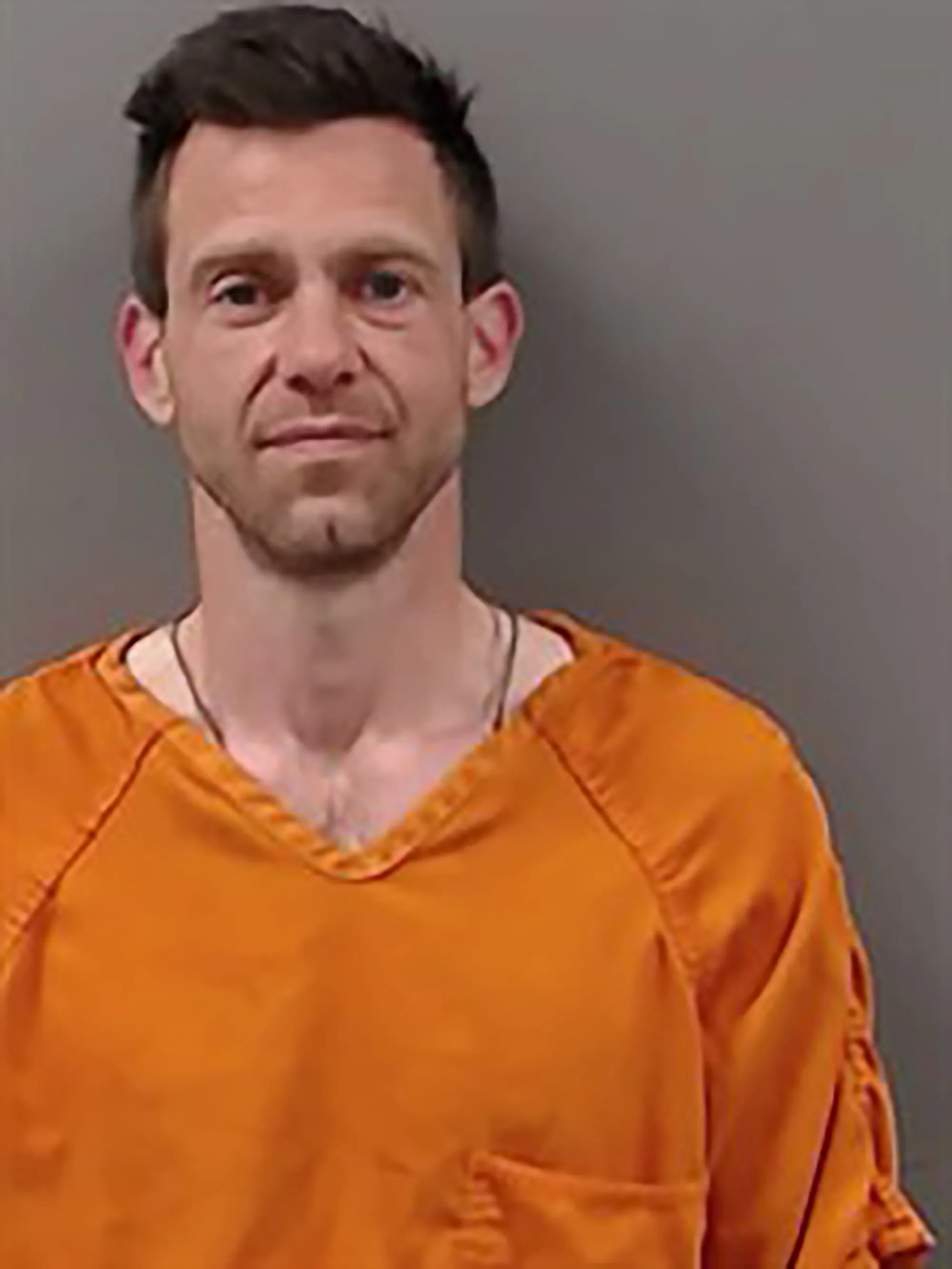 Mugshot of Brandon "Bug" Hall looking forward, wearing an orange prison jumpsuit.