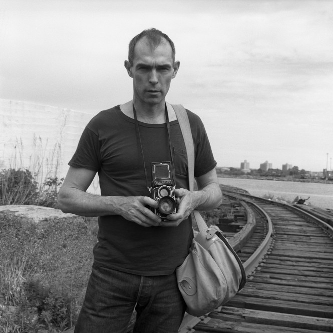 A black and white photo of Peter Hujar holding a camera