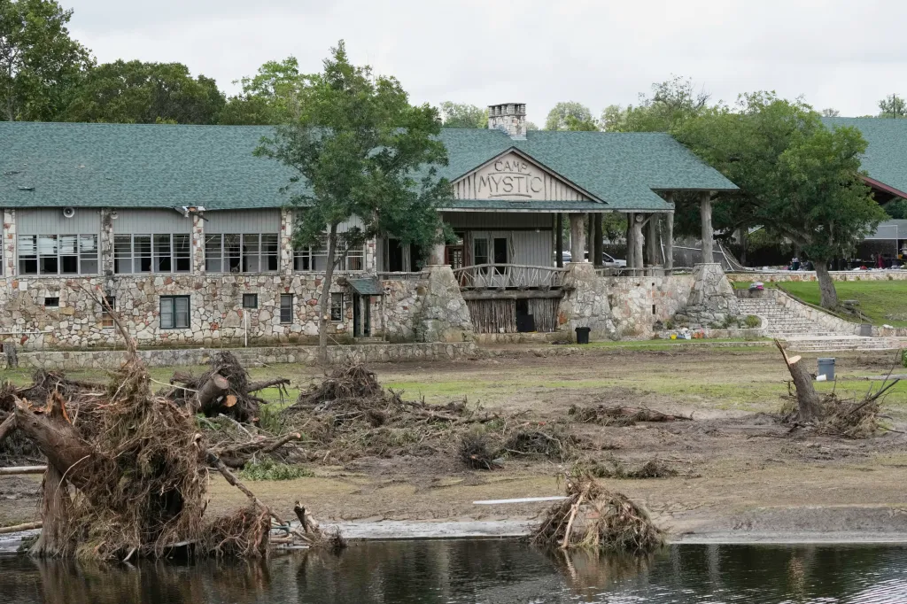 The Camp Mystic lodge in Hunt, Texas, with debris and downed trees from floods along the water's edge.