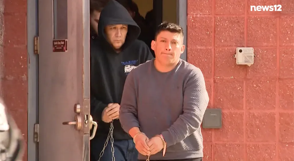 Carlos Corte, handcuffed, being walked from the Pct 6 building.