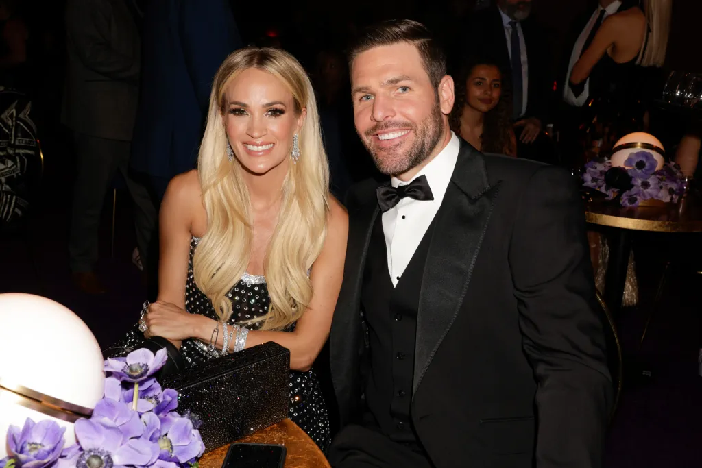 Carrie Underwood and Mike Fisher smiling at the 64th Annual Grammy Awards.