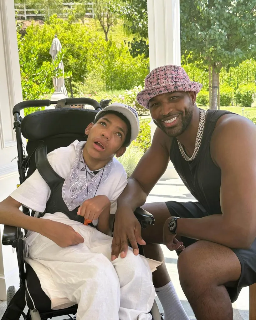 Chrissy Teigen's son Miles in a wheelchair with a man kneeling beside him.