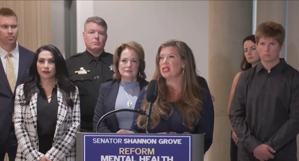 Christina Scrivner, estranged wife of Zack Scrivner, speaking at a podium with others standing nearby.