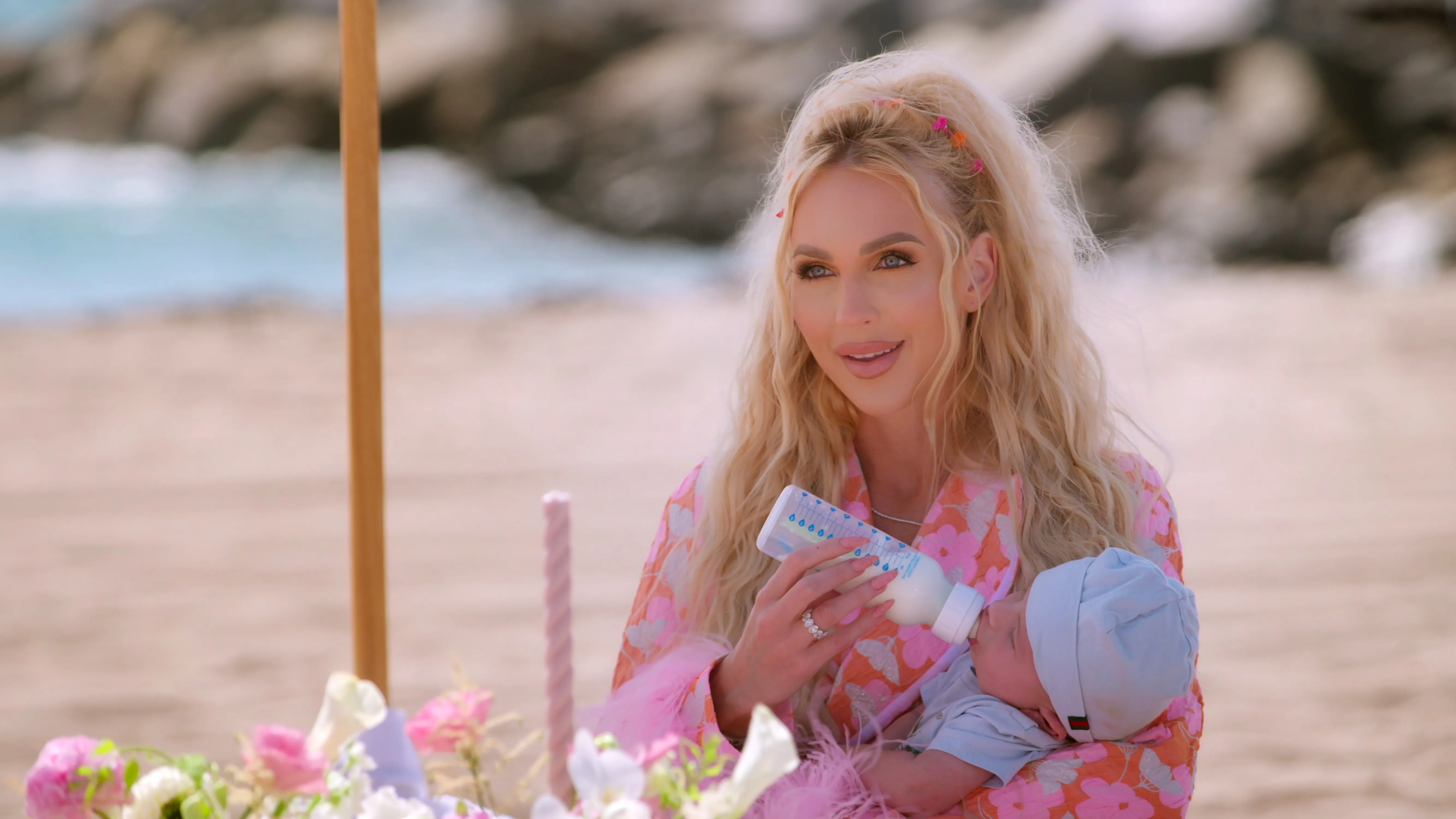 Christine Quinn feeding her baby a bottle on a beach.