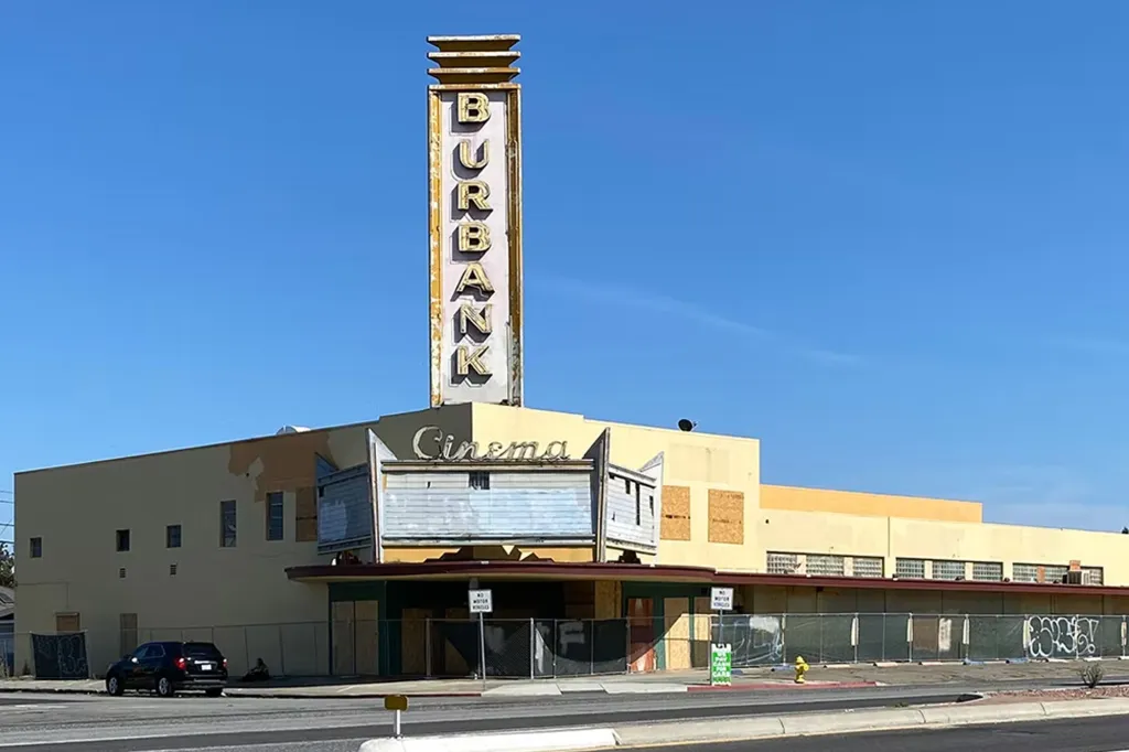 The abandoned Burbank Cinema building with its marquee boarded up and a tall, faded "Burbank" sign rising above it.