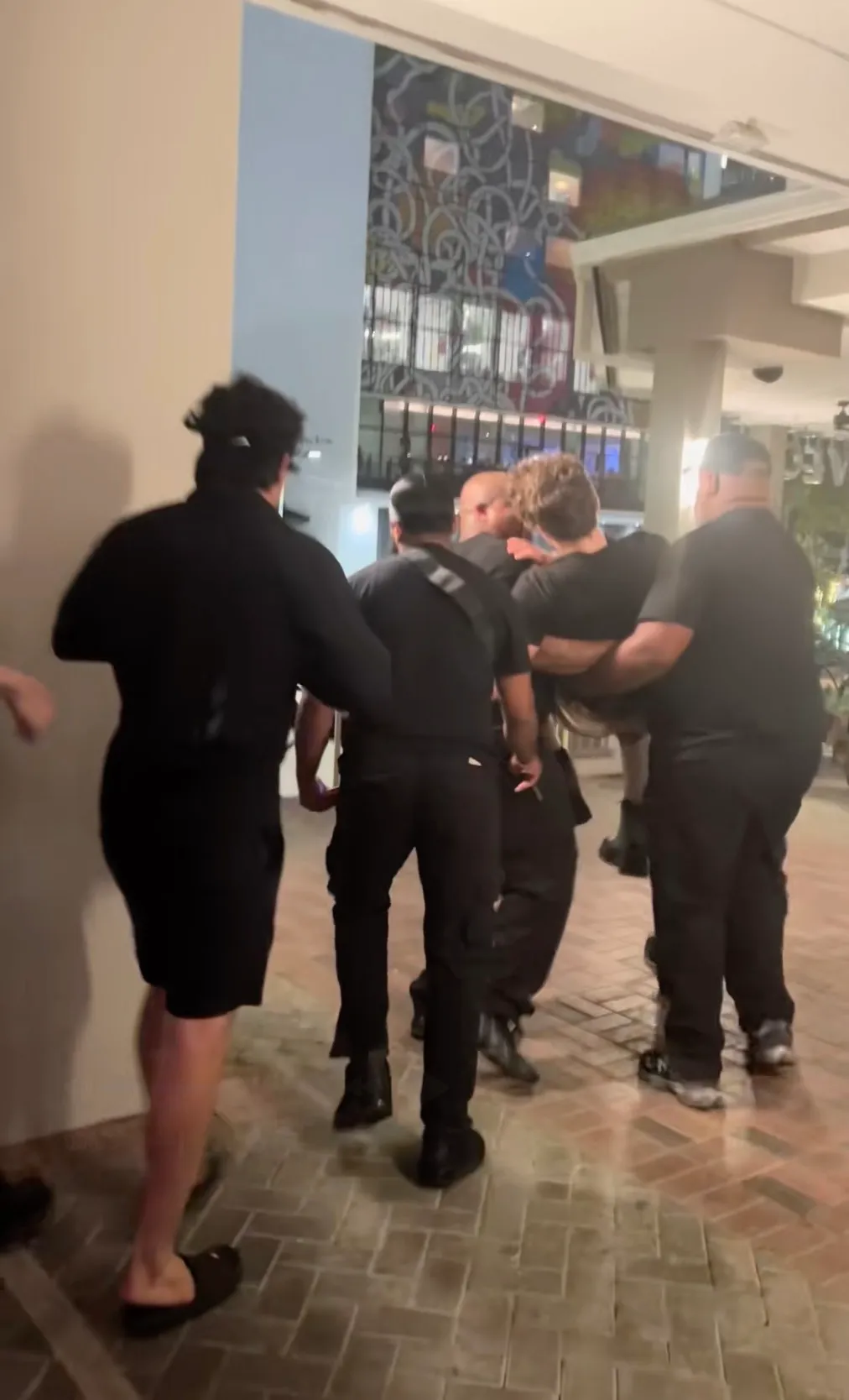 Braden Peters, a streamer, is carried out of a venue by two men in black.