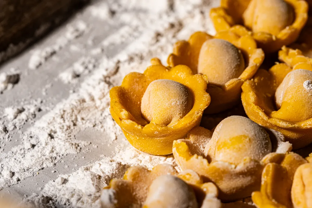 Freshly made, flour-dusted tortellini pasta, ready to cook.