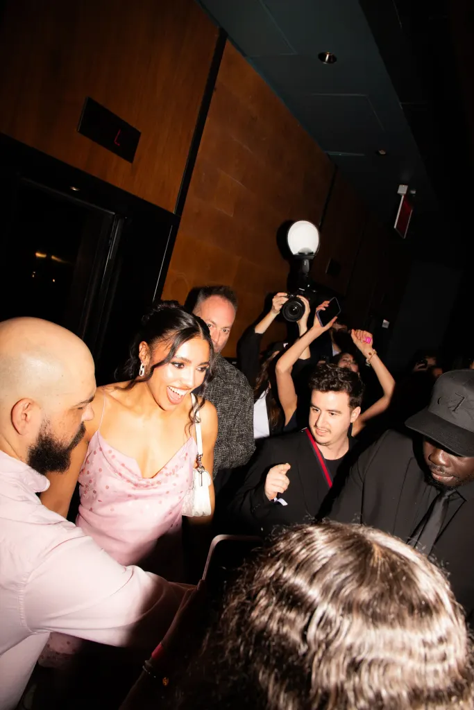 Azzi Fudd smiling, surrounded by a crowd of people, some holding up phones and cameras.