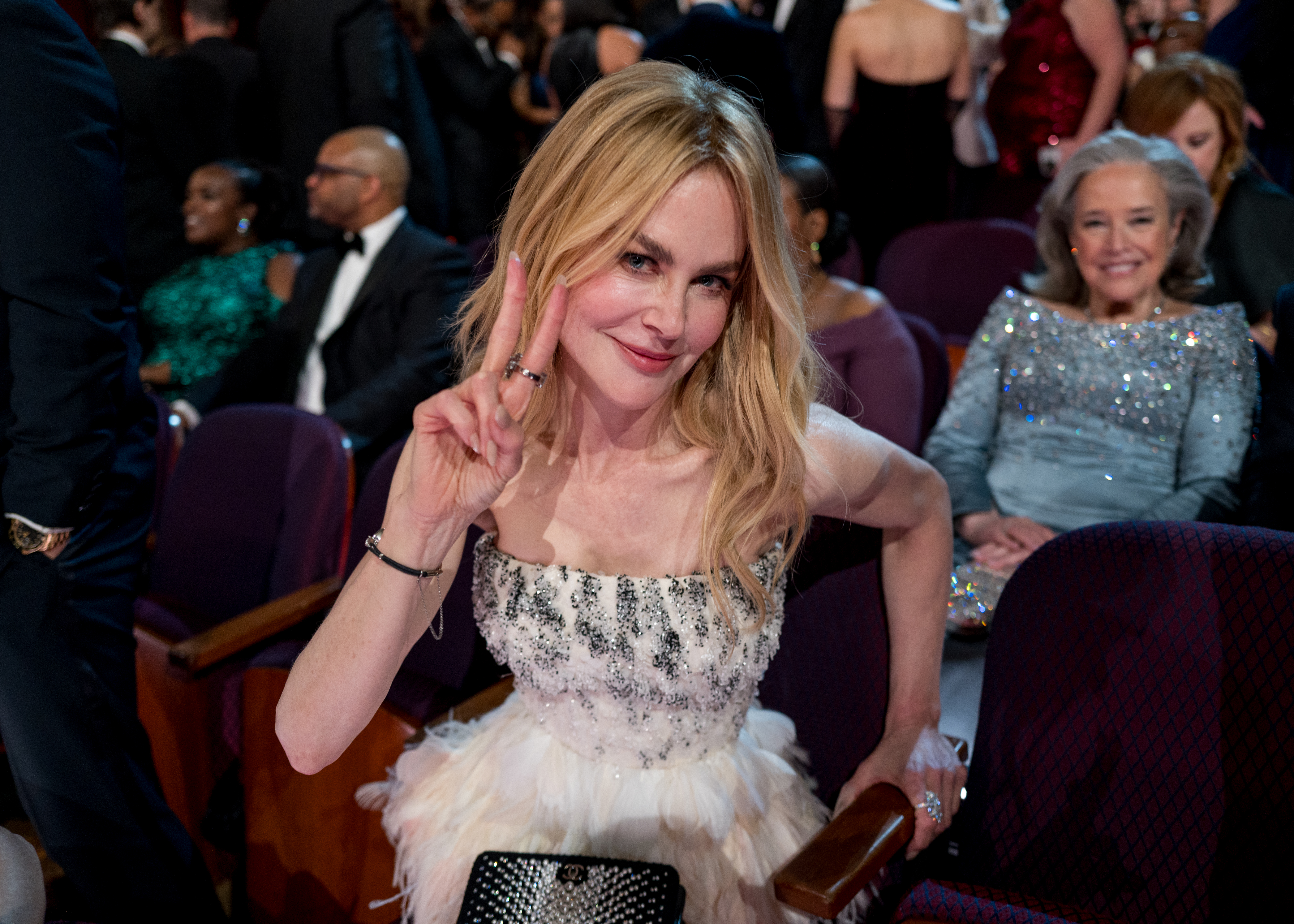 Nicole Kidman, seated in the audience at the 98th Annual Oscars, poses for a photo making a peace sign with her right hand.