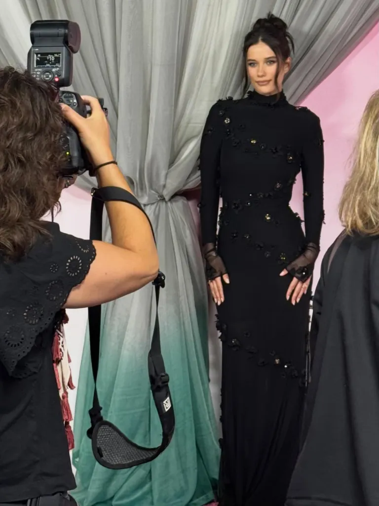 Ella Bleu in a black dress with floral embellishments being photographed.