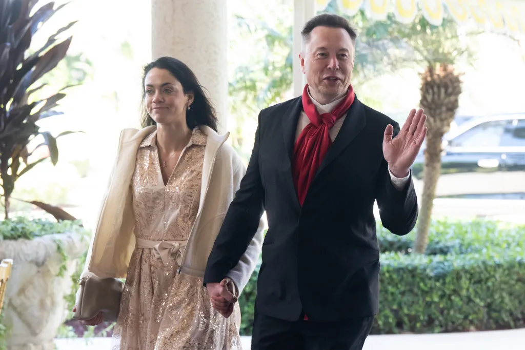 Elon Musk and Shivon Zilis hold hands, smiling as they arrive at a wedding.