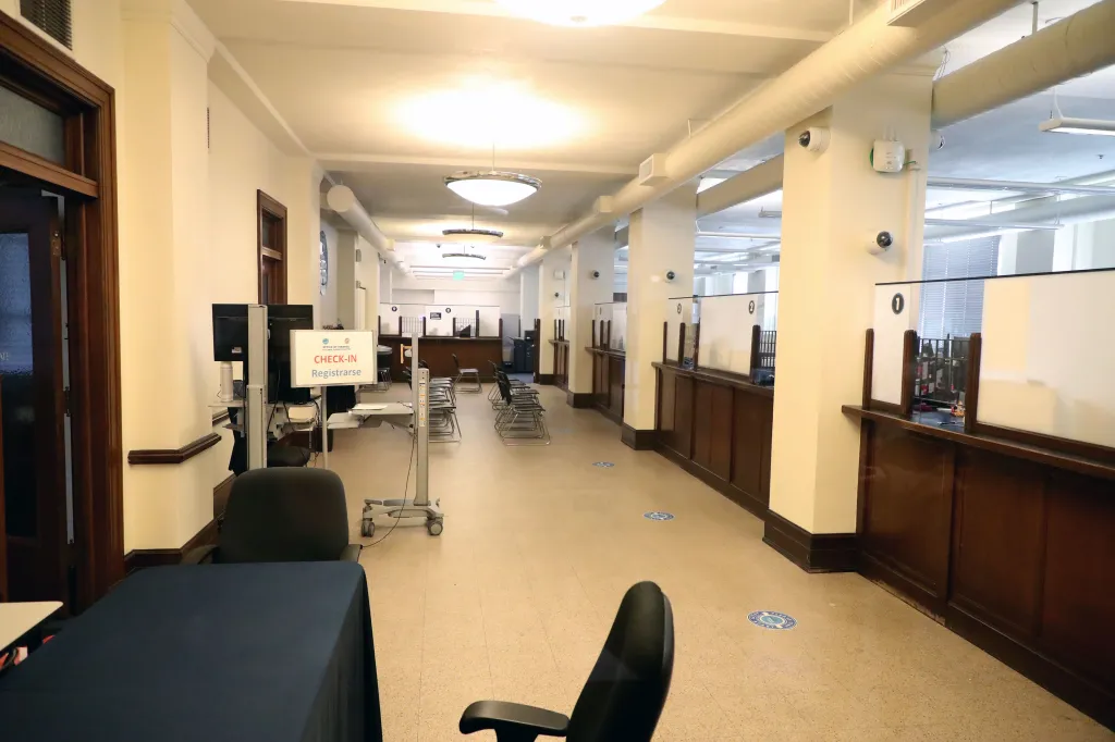 Empty City Finance Department with a "Check-In" sign, rows of empty chairs, and numbered service windows.