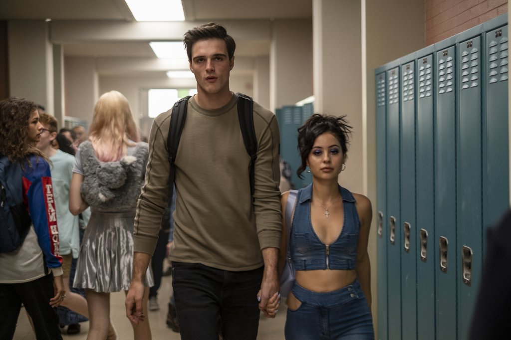 Jacob Elordi as Nate Jacobs and Alexa Demie as Maddy Perez from Euphoria, walking down a school hallway hand in hand.
