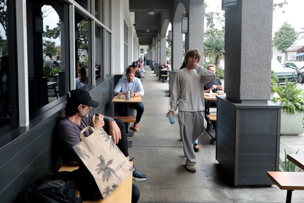 People sitting at tables and a man walking along an outdoor patio at Erewhon in Beverly Grove.