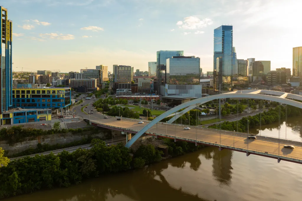 Evening aerial view of downtown Nashville, Tennessee, with the Korean Veterans Memorial Bridge over the Cumberland River, and city skyscrapers.