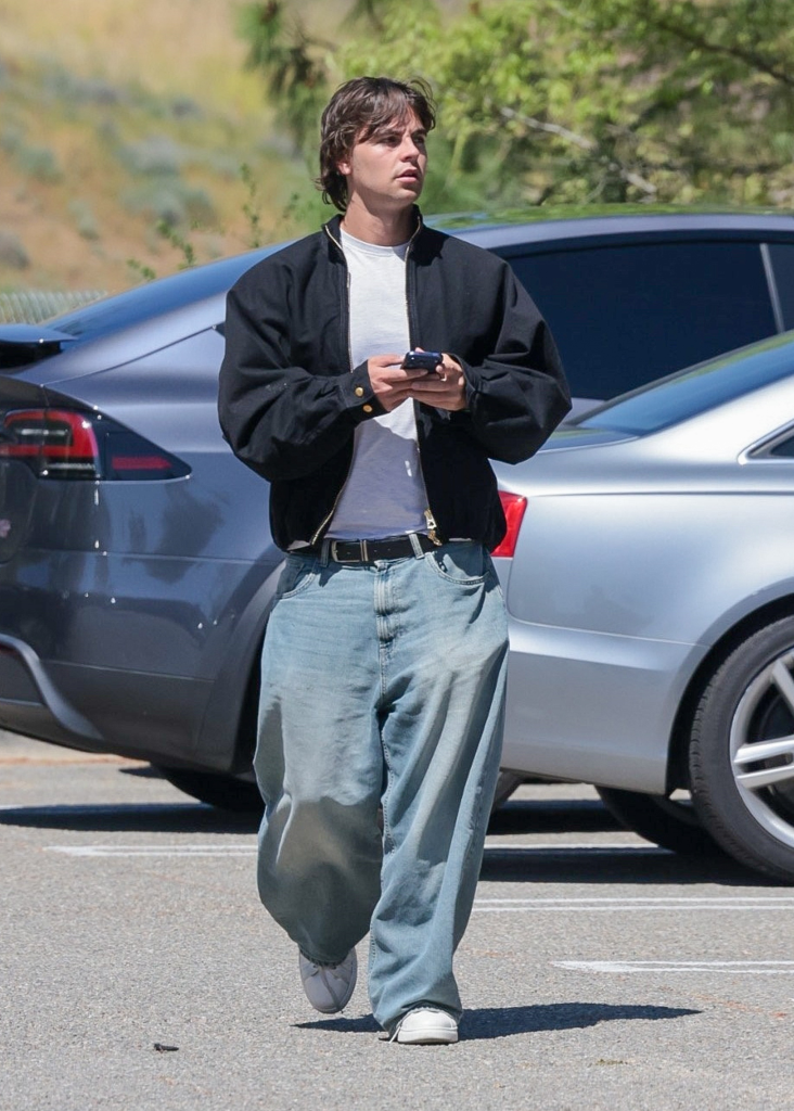 Sean Preston Federline walking in a parking lot, wearing baggy jeans and a black jacket over a white t-shirt.