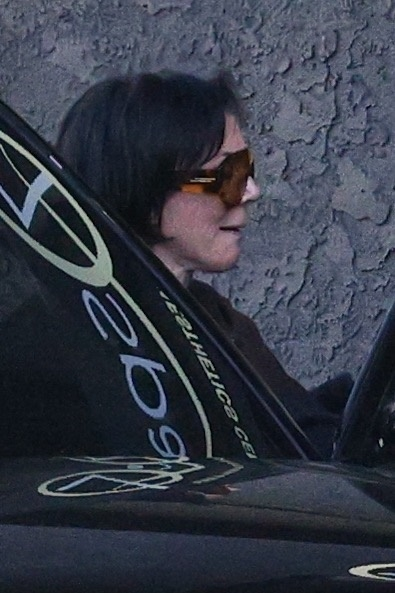 Kris Jenner in sunglasses and dark hair, seen from the side, looking forward.