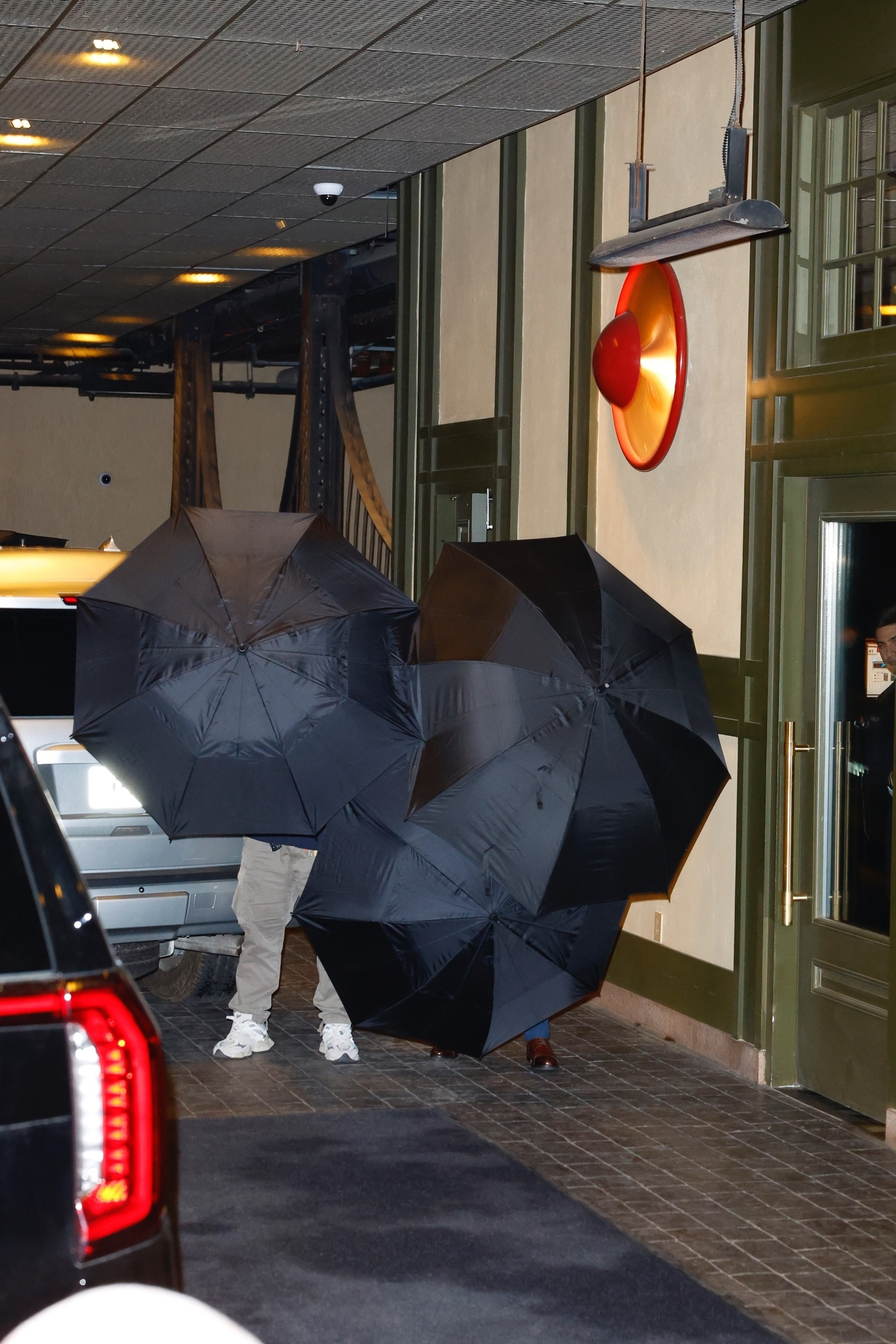 Taylor Swift and Travis Kelce hide behind umbrellas arriving at Casa Cipriani in NYC.