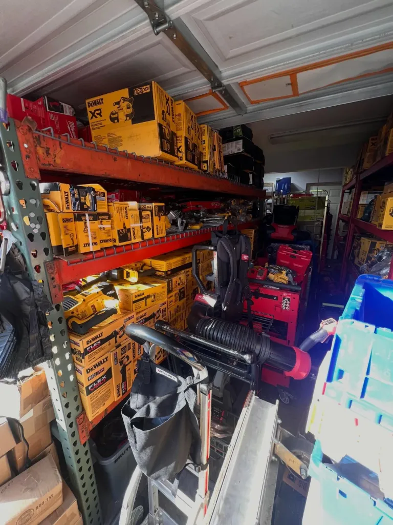A storage unit filled with new, boxed power tools, mostly from the DeWalt brand, stacked on metal shelves.
