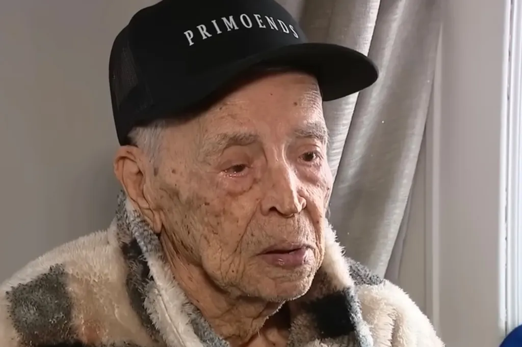 Luis Cano, 111-year-old man, wearing a "PRIMOENDS" hat and a fuzzy robe.