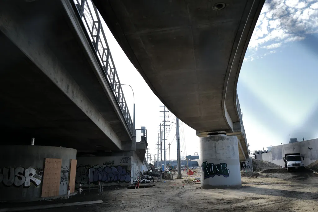 The underside of the 6th Street Bridge, with graffiti on its concrete supports and surrounding walls.