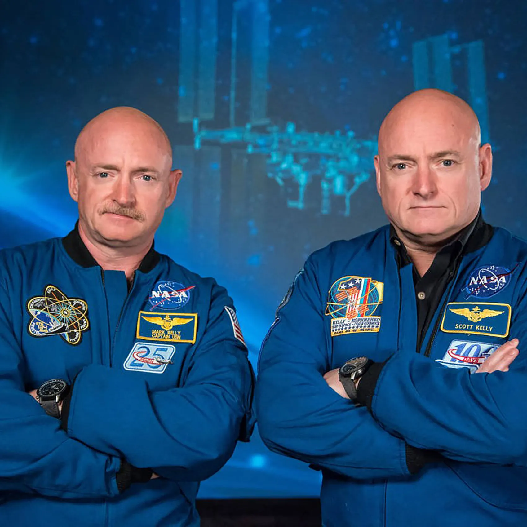 Scott and Mark Kelly in their NASA jackets with arms crossed
