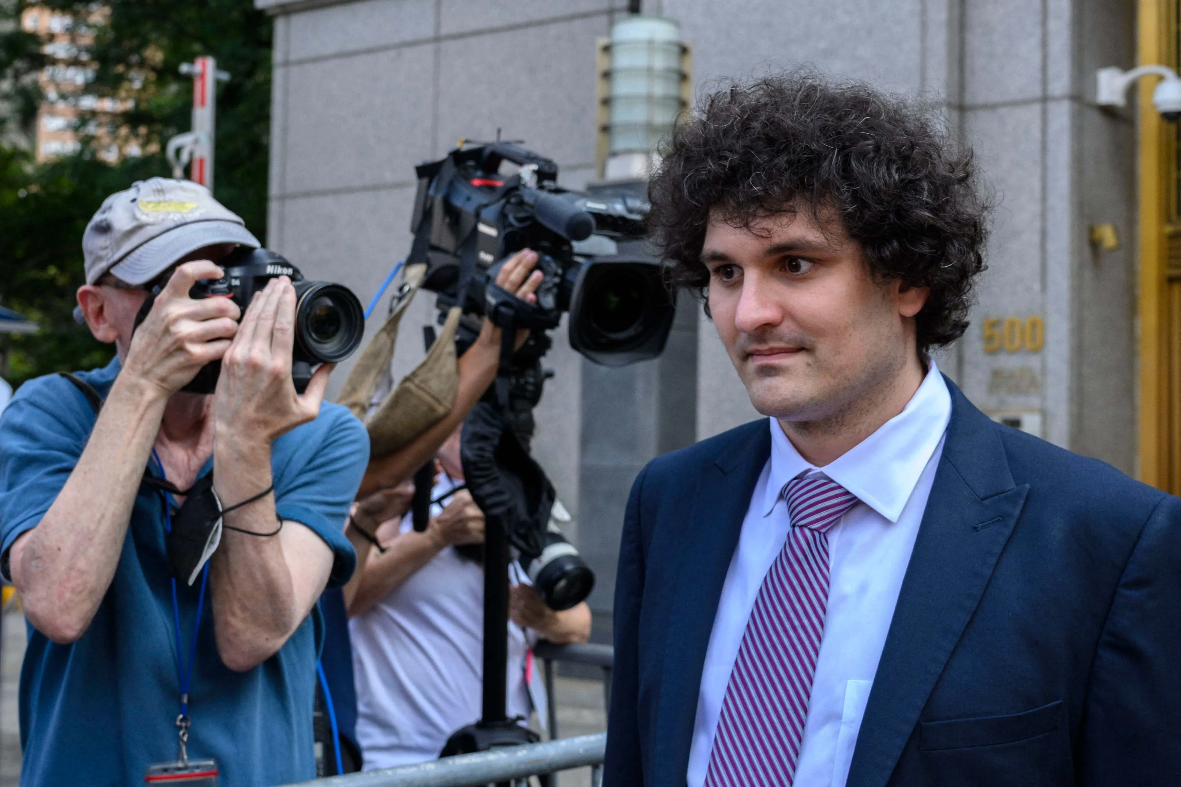 Sam Altman-Fried walks in front of photographers during his fraud trial.